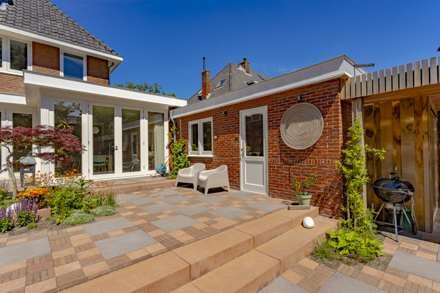 Bestrating,. ontwerp en aanleg van gezellige achtertuin met veranda in Santpoort