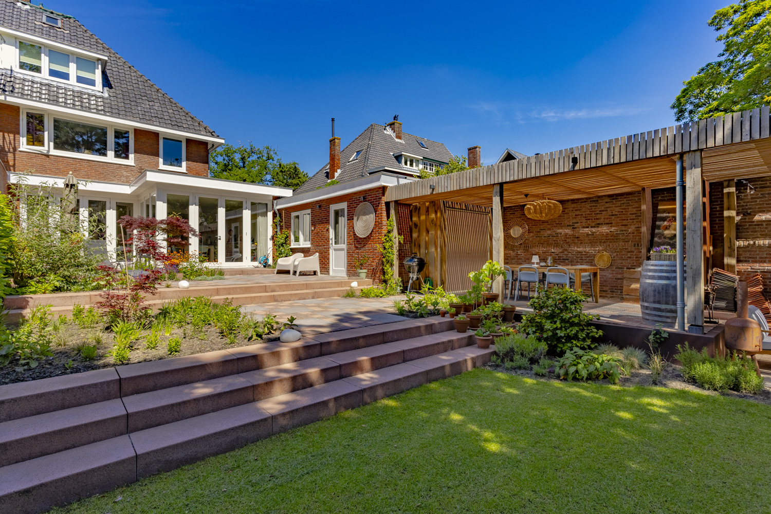 Ontwerp en aanleg van gezellige achtertuin met veranda in Santpoort